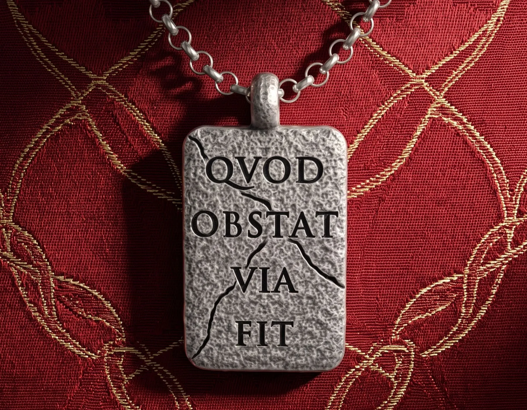 ciondolo-collana-uomo-pendente-quod-obstat-via-fit-6 ciondolo con incisione latina quod obstat via fit vista frontale sfondo seta imperale decorazioni oro
